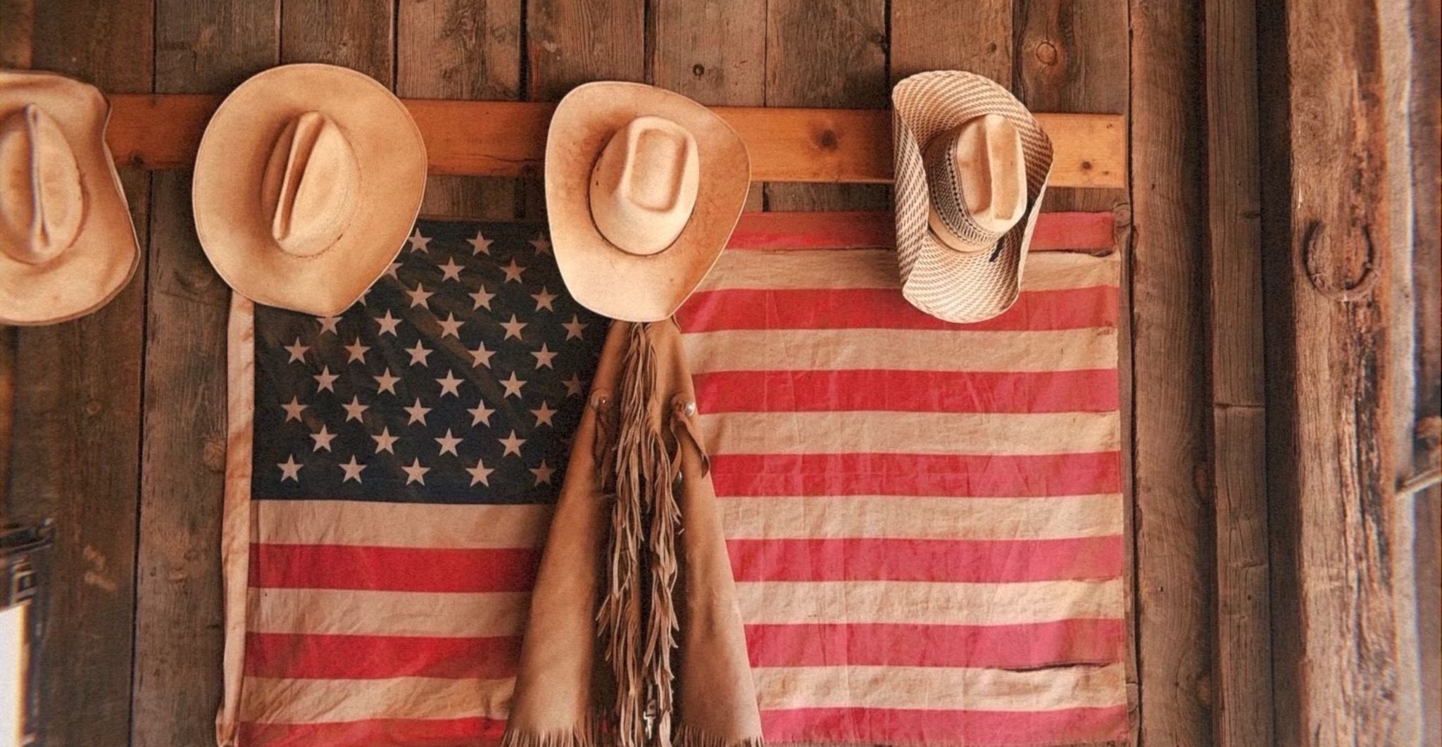 American flag hanging from a city building between tall downtown skyscrapers.