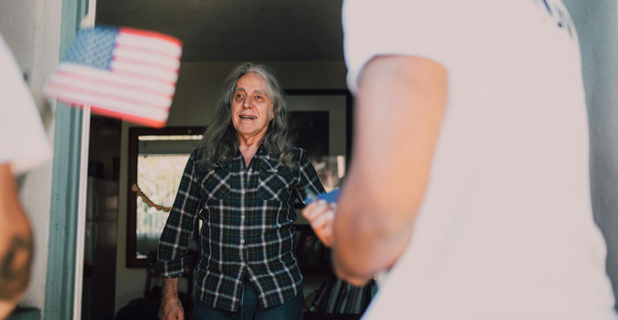 Smiling veteran standing in their doorway while greeting a visitor offering assistance